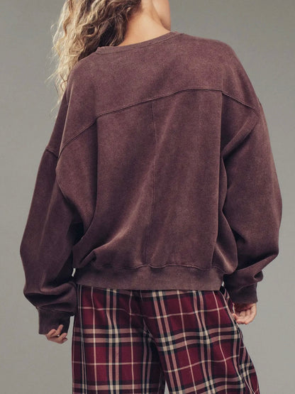 Person wearing a brown sweatshirt and plaid pants on a gray background