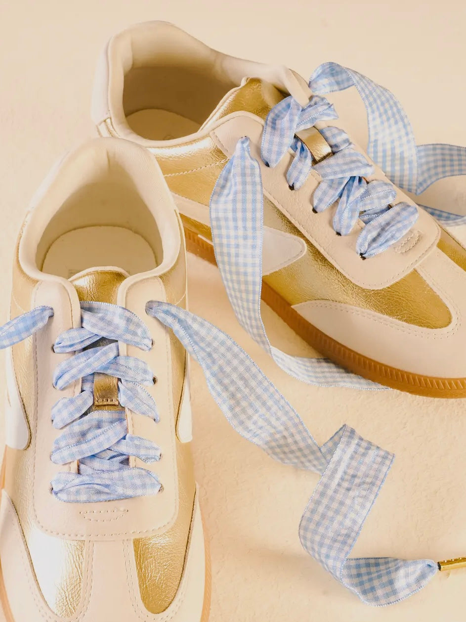 Beige sneakers with blue checkered laces on a beige background